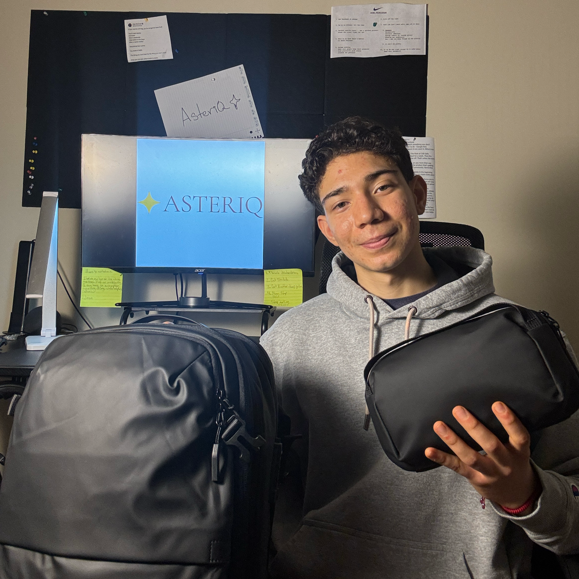 Person holding a black bag in front of a desk with a computer monitor displaying 'Asterisk'.